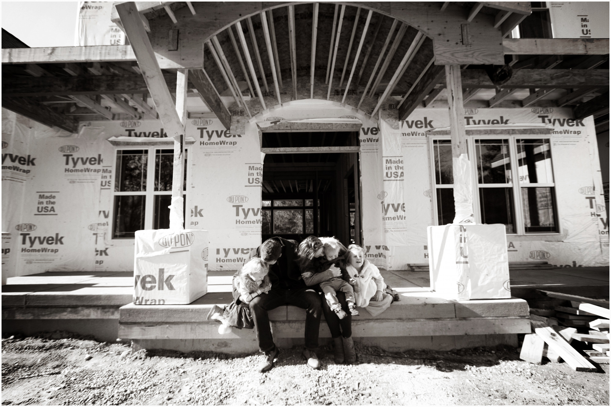 family sitting outside new construction home 